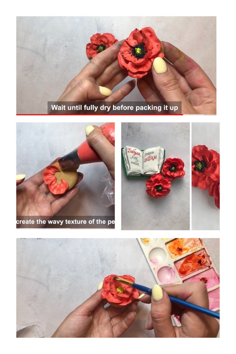 May include: A close-up of a hand holding a red felt poppy flower. The flower has a black center and is being painted with a brush. The background is a white surface with a watercolor palette.