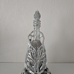 May include: A silver decorative bottle with an elaborate metal filigree design. The bottle has a narrow neck and a detailed stopper. The metalwork features a stylized, organic pattern, creating a unique and artistic appearance.