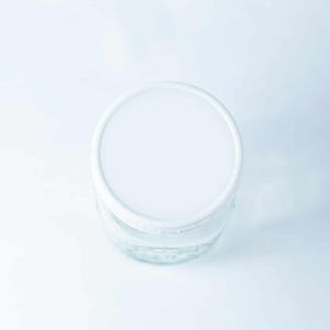 May include: A white lid on top of a clear glass jar.
