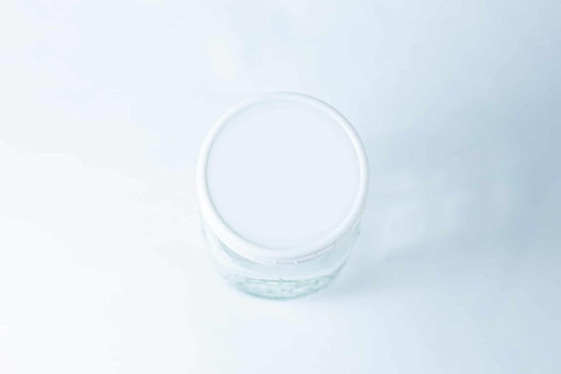 May include: A white lid on top of a clear glass jar.