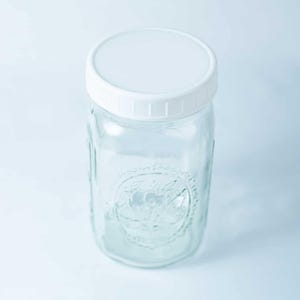 May include: A clear glass jar with a white lid. The jar has a textured design on the side.
