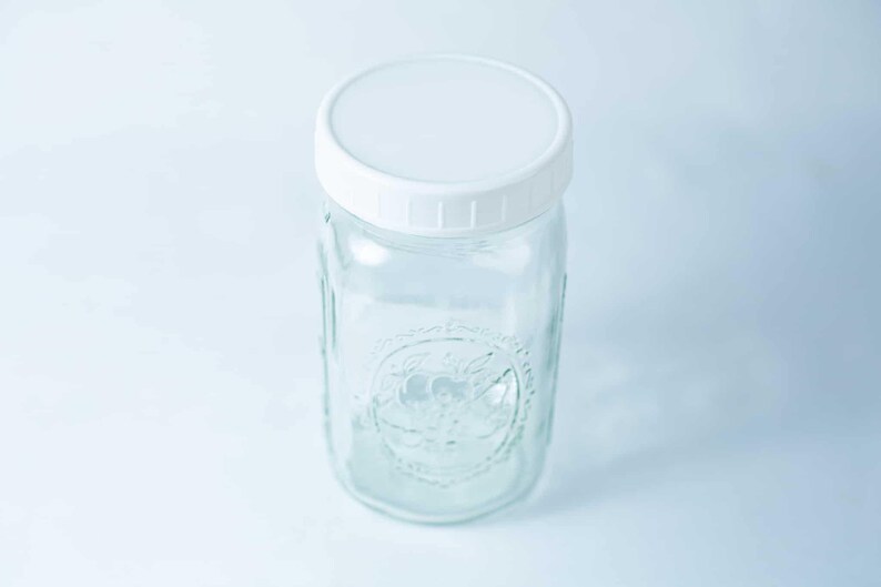 May include: A clear glass jar with a white lid. The jar has a textured design on the side.