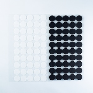 May include: A sheet of white adhesive dots and a sheet of black adhesive dots. Both sheets are on a white background.