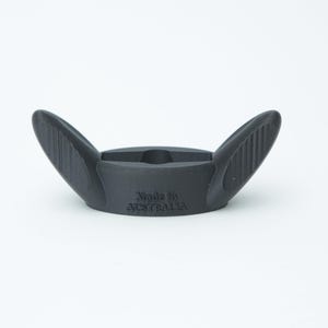 May include: A dark grey, wing-shaped object with the text "Made in AUSTRALIA" on the front. The object has a central, recessed area and two upward-curving wings with ridged detailing. The item is set against a white background.