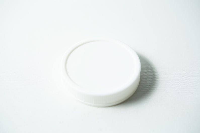 May include: A white plastic lid for a jar or container.