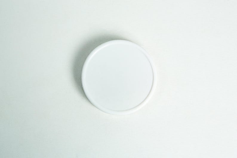 May include: A white round plastic lid for a container.