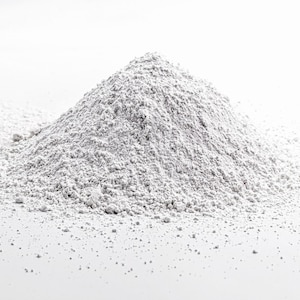 May include: A pile of white powder on a white background. The powder is fine and granular, and it is spread out in a mound shape.