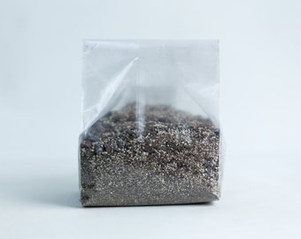 May include: A clear plastic bag filled with a dark brown and white soil-like substance.