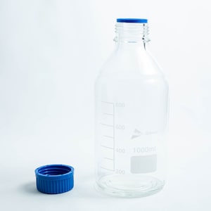 May include: A clear glass bottle with a blue lid and markings for 1000ml. The bottle is on a white surface.