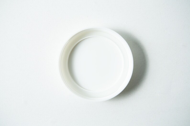 May include: A white plastic lid for a jar or container.