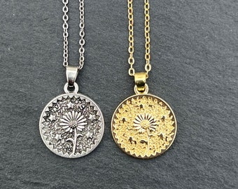 Puede incluir: Dos delicados collares con un colgante de diente de león. Un collar tiene una cadena y un colgante de plata, el otro tiene una cadena y un colgante de oro.