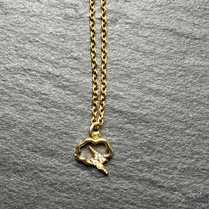 Puede incluir: Un collar de cadena dorada con un pequeño colgante de nube con un rayo con brillantes transparentes.