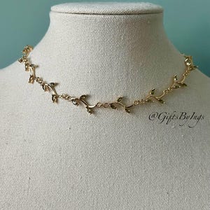 May include: Gold necklace with a delicate vine design featuring small leaves. The necklace is on a white mannequin bust. The text "@GiftsByLugs" is visible in the bottom right corner of the image.