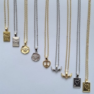 May include: A collection of necklaces with various pendant designs, including a butterfly, bee, peace sign, wings, and playing card symbols. The necklaces have either gold or silver chains and pendants, displayed against a white background.