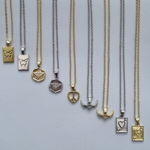 May include: A collection of delicate necklaces with various pendant designs, including butterflies, bees, peace signs, wings, and playing card symbols. The chains are silver and gold-toned, with rectangular and circular pendants.