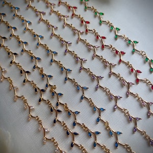 May include: A set of gold necklaces with delicate branch designs and colorful gemstone accents. The necklaces feature various colors, including blue, green, red, pink, and purple.