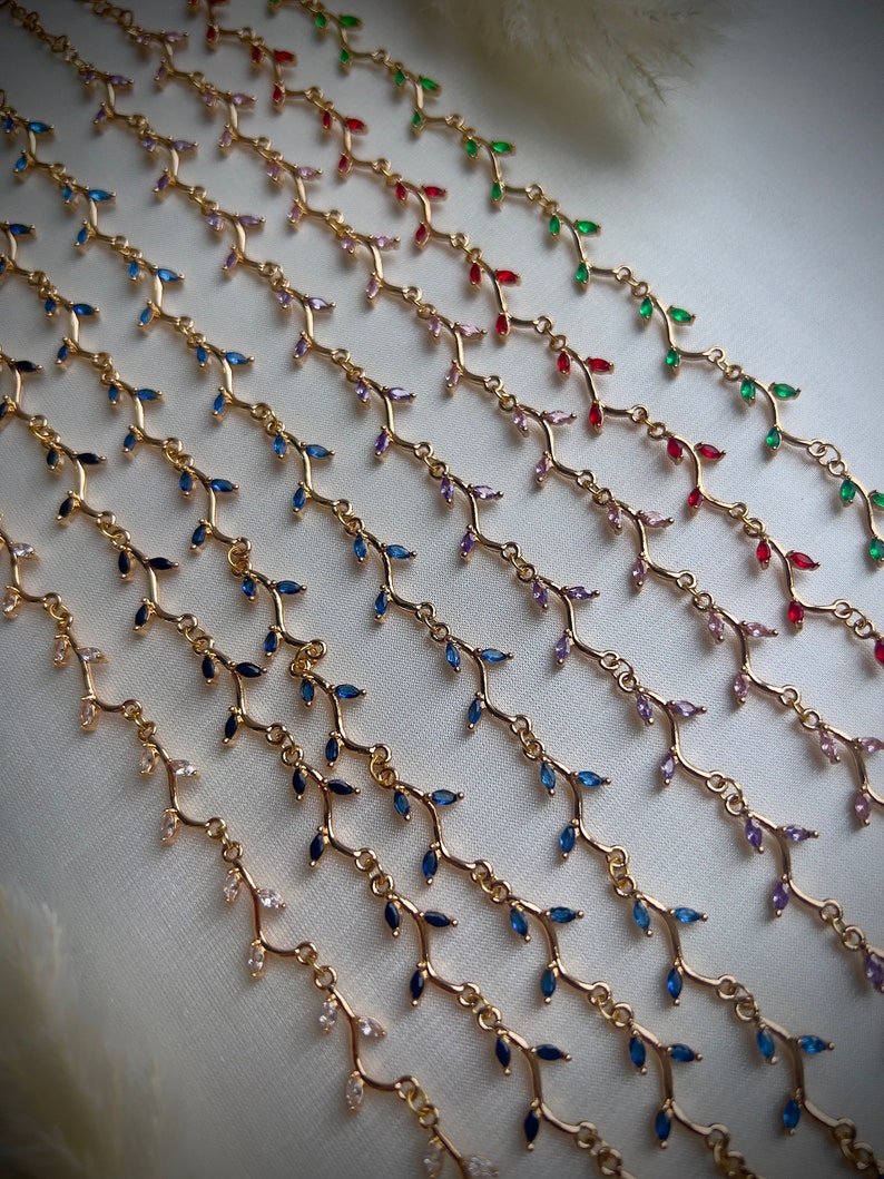 May include: A set of gold necklaces with delicate branch designs and colorful gemstone accents. The necklaces feature various colors, including blue, green, red, pink, and purple.