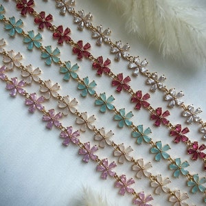 May include: A set of six gold flower chain necklaces with different colored flower accents. The necklaces feature pink, light blue, cream, and white flower accents.