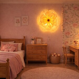 May include: A bedroom with wooden furniture, including a bed, chest of drawers, and desk. A large, illuminated flower-shaped light is on the wall. The room is decorated in soft pink tones with floral accents, creating a warm atmosphere.