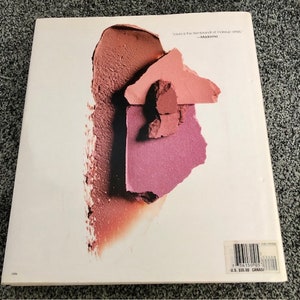 May include: A close-up of a book cover with a pink, red, and brown makeup swatch. The text on the cover reads "'Stila is the Rembrandt of makeup artists.' -Madonna"