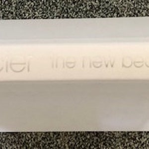 May include: White book with the title "laura mercier the new beauty secrets" printed on the spine.