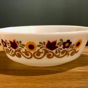 May include: White ceramic baking dish with a floral design in shades of brown, orange, and red. The design features stylised leaves, flowers, and swirls.