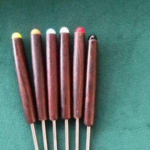 Può includere: Set di sei forchette da fonduta con manici in legno scuro e punte colorate. Le punte sono gialle, arancioni, bianche, rosse e nere. Le forchette hanno lunghe e sottili punte argentate. Lo sfondo è di colore verde.