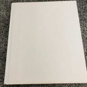 May include: A blank white hardcover book with a smooth surface.