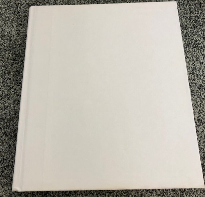 May include: A blank white hardcover book with a smooth surface.