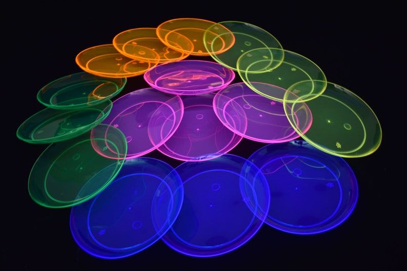 May include: A stack of neon-colored plastic plates in green, blue, purple, and orange. The plates are stacked in a pyramid shape.