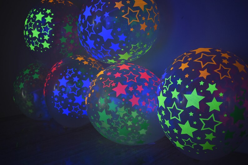 May include: A group of colorful balloons with star patterns. The balloons are translucent and glow in the dark. The colors of the stars are green, blue, red, and orange.
