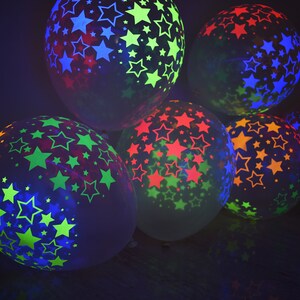 May include: A group of six glow-in-the-dark balloons with star patterns in various colors, including green, blue, red, and yellow.