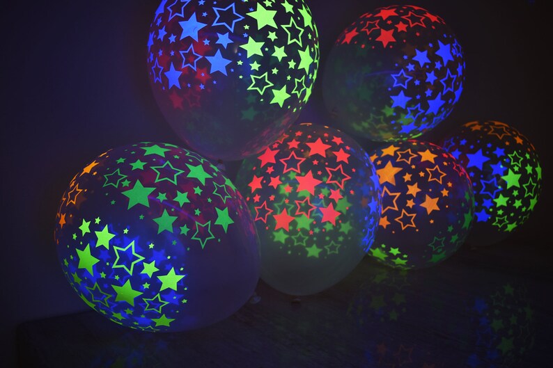 May include: A group of six glow-in-the-dark balloons with star patterns in various colors, including green, blue, red, and yellow.