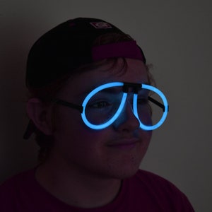 May include: A person wearing a black baseball cap and blue glow-in-the-dark glasses.