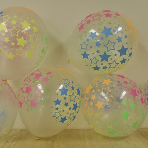 May include: A group of six clear balloons with a star pattern. The stars are in various colors, including yellow, blue, green, and pink.