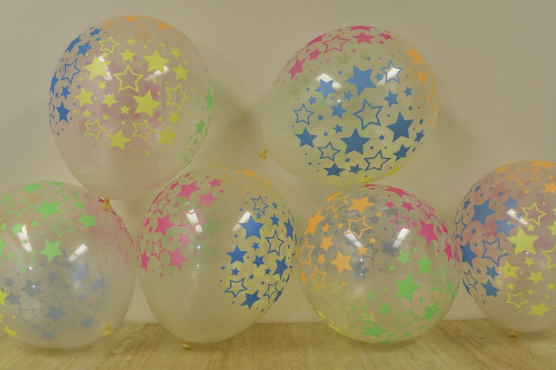 May include: A group of six clear balloons with a star pattern. The stars are in various colors, including yellow, blue, green, and pink.