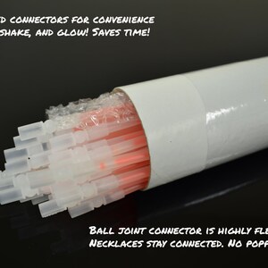 May include: A bundle of orange glow sticks with preattached translucent plastic connectors housed in a white cylindrical tube. The tube features an orange sticker with the text ORANGE. Text on the image reads PREATTACHED CONNECTORS FOR CONVENIENCE JUST SNAP, SHAKE, AND GLOW! SAVES TIME! and BALL JOINT CONNECTOR IS HIGHLY FLEXIBLE NECKLACES STAY CONNECTED. NO POPPING OUT!
