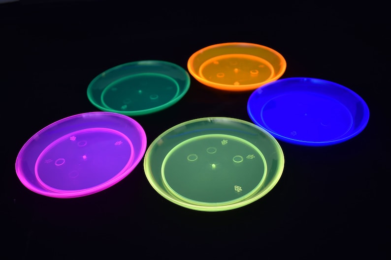May include: Five plastic saucers in different neon colors: green, orange, blue, purple, and yellow. The saucers are all the same size and shape, and they are arranged in a circle.