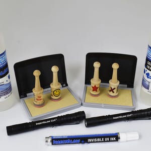 May include: An assortment of DirectGlow LLC products, including two bottles of liquid, two stamp pads with wooden stamps, two black UV flashlights, and a tube of invisible UV ink. The stamps have various designs.