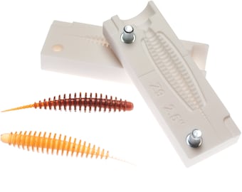 May include: White plastic mold for making fishing lures. The mold is open and shows the shape of the lure. Two finished lures are shown below the mold. One is brown and the other is orange.