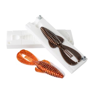 May include: A white plastic mold for making fishing lures, with a brown and orange lure already made in the mold.