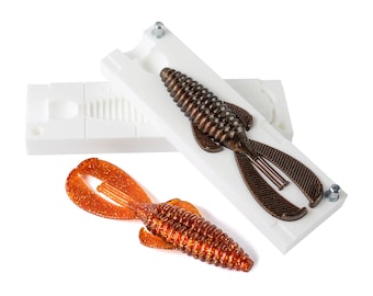 May include: A white plastic mould for making fishing lures, with a brown and orange lure already made in the mould.