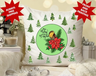 May include: White throw pillow with a green circle featuring a robin, a red poinsettia, and the text "'Tis the season to be merry and bright". The background is filled with green pine trees.