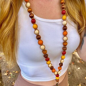 May include: A beaded lanyard with brown, orange, red, and white beads. The lanyard has a key ring attached to the bottom.
