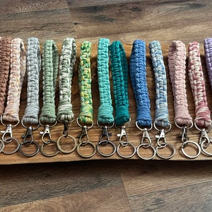 May include: A collection of 20 colorful crocheted keychains with metal key rings. The keychains are made with different colored yarn and have a variety of patterns.