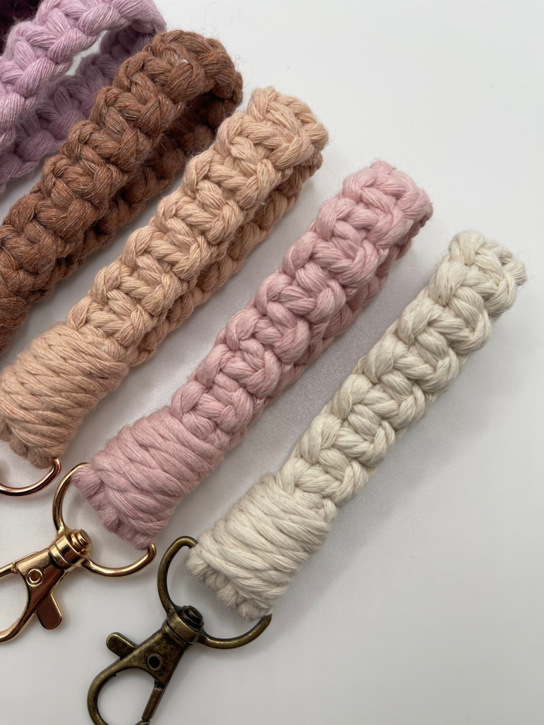 May include: Four crocheted keychains in shades of brown, beige, pink, and white with gold and bronze key rings.