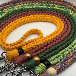 May include: A set of five colorful crocheted lanyards with different colored beads and metal clasps. The lanyards are made with a variety of colors, including yellow, green, red, and blue.