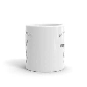 May include: White ceramic mug with a black line drawing of a tree and the text "Wildwood Crest, NJ" and "Wildwood, NJ". The mug is cylindrical and has a handle.