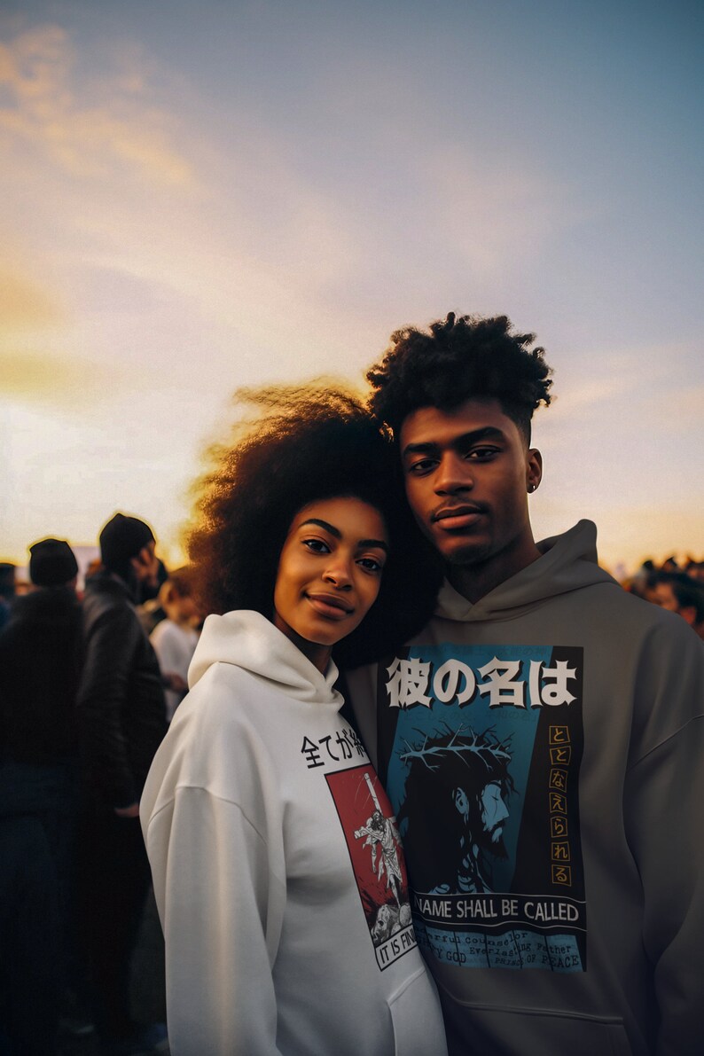 May include: Two people wearing hoodies with graphic designs. The person on the left is wearing a white hoodie with Japanese text and a graphic of a person on a cross. The person on the right is wearing a gray hoodie with Japanese text and a graphic of Jesus on a cross. The text on the hoodie says "His name shall be called".