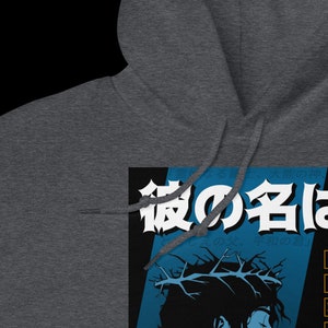 May include: A dark gray hooded sweatshirt with a graphic print of a person with a crown of thorns and the Japanese text "夜の手は" on a blue and black background.